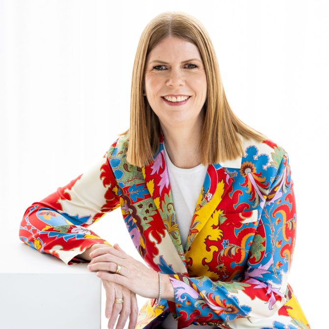 Sonya Beyers is the Chair of the Board of Southern Cross Care Tasmania and is shown seated wearing a colourful jacket.